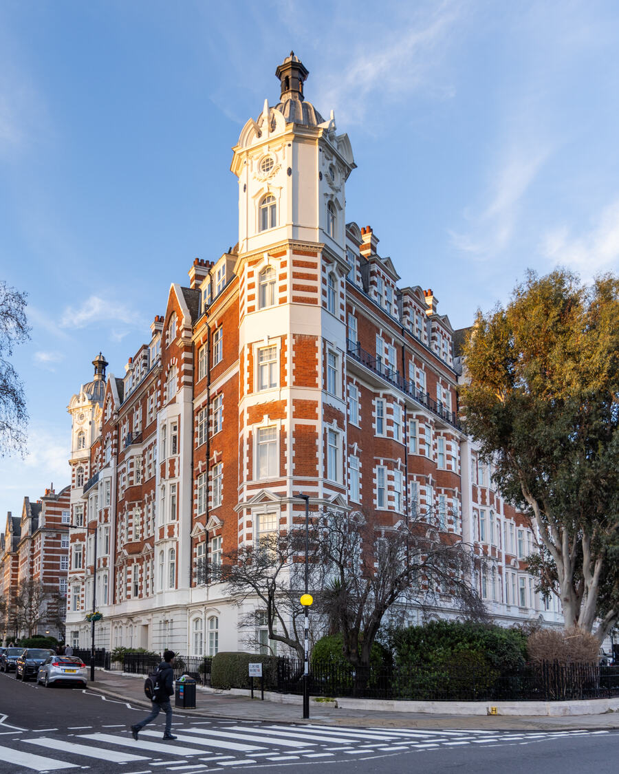 Period red-brick corner building with turret and white stone detailing, framed by trees