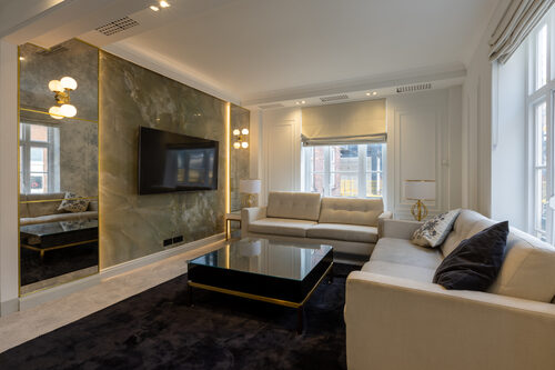 Refurbished open-plan living room with marble feature wall and designer lighting